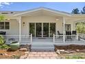 Charming covered porch with white railings, inviting seating, and manicured landscaping at 4223 Eldorado Springs Dr, Boulder, CO 80303