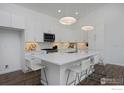 Well-lit kitchen featuring an island, hardwood floors, and white cabinets and appliances at 729 Kubat Ln # A, Longmont, CO 80503
