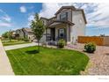 A quaint two-story home with a covered porch and well-manicured lawn sits on a sunny street at 7414 Blue River Ave, Frederick, CO 80530
