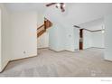 Spacious living room featuring neutral carpet, staircase, and access to other living spaces at 988 Cleveland Ct, Louisville, CO 80027