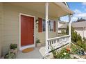 Inviting front porch with a red door, white railing, and colorful flower beds at 1026 Red Oak Dr, Longmont, CO 80504