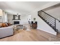 Open-concept living room featuring a fireplace, hardwood floors, and staircase at 10430 Owens Cir, Broomfield, CO 80021