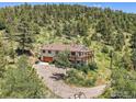 Scenic home with a large wooden deck, surrounded by trees, offering serene mountain living at 13976 Wamblee Trl, Conifer, CO 80433