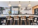 The open kitchen features stainless steel appliances, bar seating, and stylish pendant lighting at 1405 Clover Creek Dr, Longmont, CO 80503