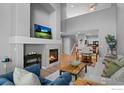 Bright living room featuring a stone fireplace, high ceilings, hardwood floors, and a view to the kitchen at 14300 Waterside Ln # E3, Broomfield, CO 80023