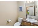 Cozy half bath featuring a toilet, sink, and framed art at 1613 Alpine Ave, Berthoud, CO 80513