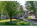Exterior side view showing a gray house with white trim, a green lawn and mature trees at 222 Vivian St, Longmont, CO 80501
