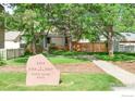 Home exterior with stone signage, mature trees, lush lawn, and an inviting walkway at 2325 N Shore Dr, Longmont, CO 80503