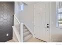 Entryway staircase with modern hexagonal tile accent wall and white door at 2763 Bear Springs Cir, Longmont, CO 80503
