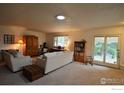 Bright living room with large windows, neutral carpet, and access to a patio at 3814 Columbia Dr, Longmont, CO 80503