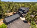 Expansive aerial view of gray home, garage, and driveway surrounded by a lush landscape at 8987 Village Pines Cir, Franktown, CO 80116
