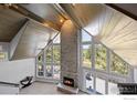 Bright living room with fireplace, vaulted ceilings, and large windows offering scenic views at 8987 Village Pines Cir, Franktown, CO 80116