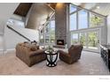 Bright living room with a fireplace, vaulted ceilings, and large windows with natural light at 8987 Village Pines Cir, Franktown, CO 80116
