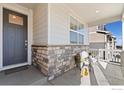 Inviting front porch with stone accents, a cozy seating area, and a view of the neighborhood at 9873 Ceylon St, Commerce City, CO 80022