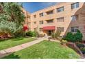 Brick apartment complex with lovely courtyard, mature trees, and inviting red awning covered entrances at 1100 Colorado Blvd # 305, Denver, CO 80206