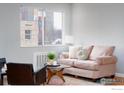 Bright living room featuring a cozy pink sofa, stylish mid-century coffee table, and large window at 1100 Colorado Blvd # 305, Denver, CO 80206