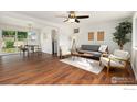 Bright living room boasts hardwood floors, a ceiling fan, and ample natural light at 1104 Village Dr, Fort Lupton, CO 80621