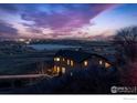 Home exterior view features a distant city, lake, and a colorful night sky at 11730 Pointe View Dr, Longmont, CO 80503