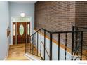 Foyer with hardwood floors, brick wall, and staircase with metal railings at 13313 W Utah Cir, Lakewood, CO 80228