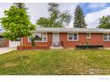 Well-kept red brick house featuring a lush green lawn and tidy landscaping at 1345 Northwestern Rd, Longmont, CO 80503