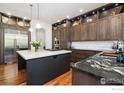 Gourmet kitchen featuring custom wood cabinets, a center island, and stainless steel appliances at 2121 Jade Way, Longmont, CO 80504