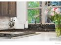 Kitchen sink with elegant fixtures and granite countertop overlooking greenery outside the window at 2121 Jade Way, Longmont, CO 80504