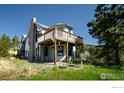 Exterior view showcasing a two-story home with a wooden deck and a stone chimney against a wooded backdrop at 237 Puma Dr, Boulder, CO 80302