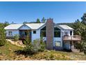Charming home exterior featuring a stone chimney, large windows, and a spacious wooden deck with scenic views at 237 Puma Dr, Boulder, CO 80302