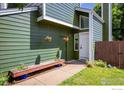 Close up of a green home's entrance with hanging baskets and a wooden bench with blue accents at 4129 Amber St, Boulder, CO 80304