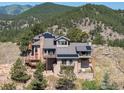 Exterior view of a home with a stone chimney, multi-level decks, and a mountain backdrop at 6183 Red Hill Rd, Boulder, CO 80302