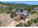 Exterior view featuring the property's stone chimney, multi-level decks, and stunning mountain backdrop at 6183 Red Hill Rd, Boulder, CO 80302