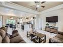 Open-concept living room with modern furniture and a ceiling fan, flowing into the kitchen at 7840 Cattail Grn, Frederick, CO 80530