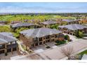 Aerial view of a residential area with townhomes, landscaping, and a golf course in the background at 1122 Olympia Ave # 12H, Longmont, CO 80504