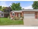 Inviting home with a two-car garage, well-kept lawn, and colorful flowers framing the entrance at 1443 Elmhurst Ct, Longmont, CO 80503