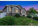 Twilight view of a well-manicured home featuring a three-car garage and lush green lawn at 1531 Alpine Ave, Berthoud, CO 80513