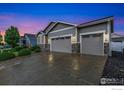 A wide driveway leads to a three-car garage with stone accents and exterior lighting at 1531 Alpine Ave, Berthoud, CO 80513