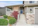 Inviting front porch and entrance featuring stone accents, manicured landscaping and updated exterior lighting at 1725 Exeter St, Berthoud, CO 80513