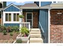 Close-up of the home's entrance, featuring a cozy porch, colorful flowerbeds, and a brick facade at 3593 S Gibralter Cir, Aurora, CO 80013