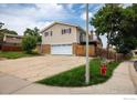 Two-story home with a two car garage, a well maintained lawn, and a fenced backyard at 7210 Otis Ct, Arvada, CO 80003