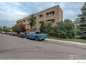 Street view of apartment complex featuring mature trees, manicured lawn, and ample parking at 733 E 2Nd Ave # 307, Denver, CO 80203