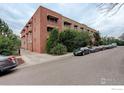 Street view of brick apartment building with mature landscaping and ample street parking at 733 E 2Nd Ave # 307, Denver, CO 80203