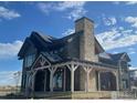 Craftsman-style home under construction featuring a stone chimney, dark siding, and a covered front porch at 917 Latigo Loop, Lafayette, CO 80026