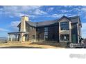A large, modern house featuring a stone chimney, dark wood elements, and under construction features at 917 Latigo Loop, Lafayette, CO 80026