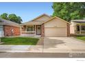 Charming brick home featuring a two-car garage, covered porch and landscaped front yard at 11156 W 64Th Pl, Arvada, CO 80004