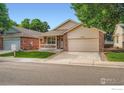 Charming brick home featuring a two-car garage, covered porch and landscaped front yard at 11156 W 64Th Pl, Arvada, CO 80004