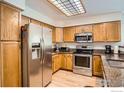 Bright kitchen with stainless steel appliances, granite counters, and wood cabinets at 11156 W 64Th Pl, Arvada, CO 80004