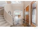 Grand foyer with a winding staircase and elegant tile flooring, leading to a bright living space at 145 Brittany Ln, Lafayette, CO 80026
