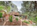 Lovely green home exterior with multiple decks and stone steps, nestled within a scenic treed landscape at 160 Valley Ln, Boulder, CO 80302