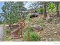 Charming home exterior featuring stone stair and wood deck, nestled in a natural hillside setting at 160 Valley Ln, Boulder, CO 80302