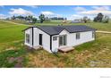 Charming single-story home with white siding, black trim, and a black roof nestled on a grassy lot at 18674 County Road 3, Berthoud, CO 80513